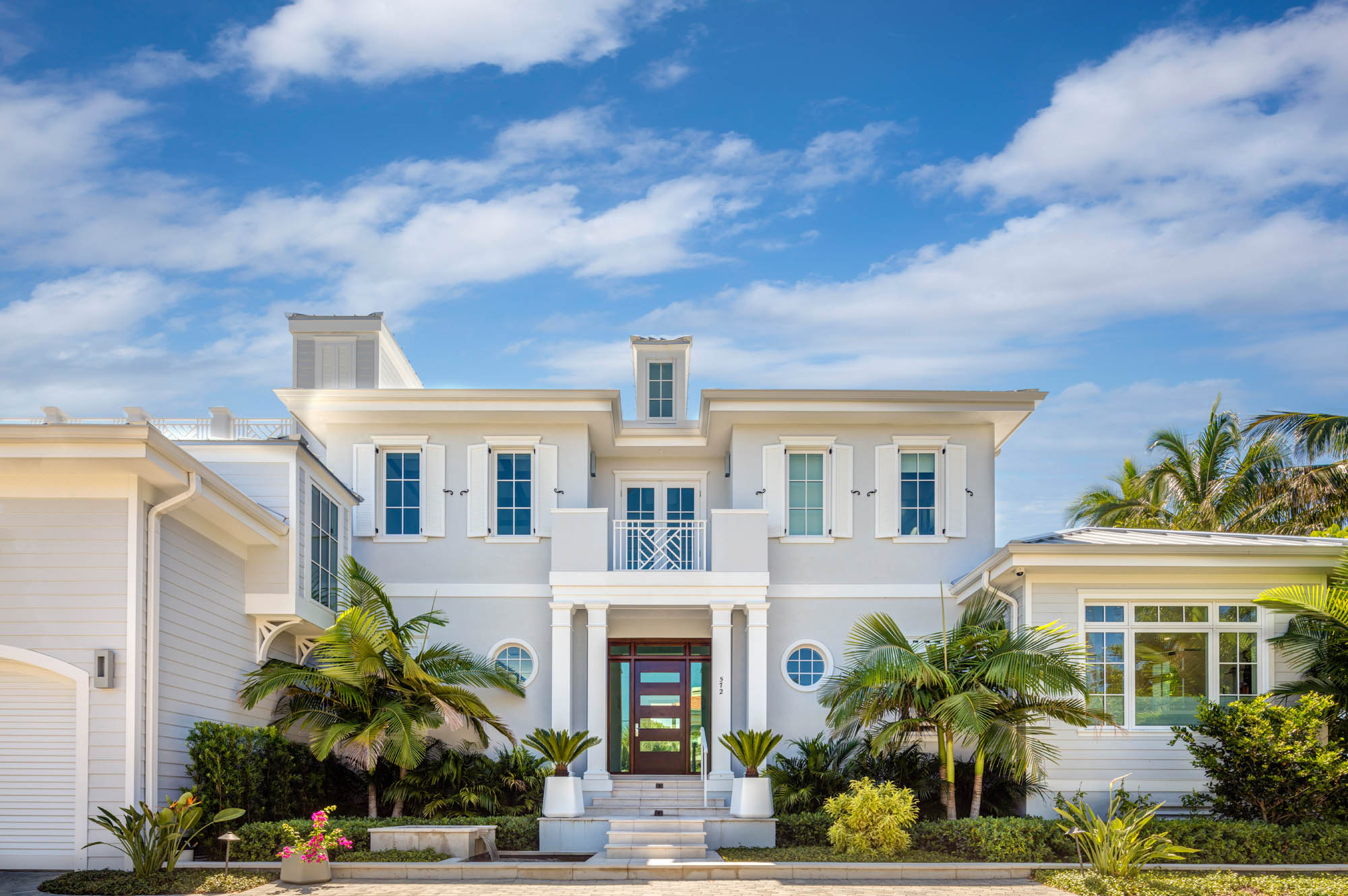 Contemporary waterfront home with elevated massing, hurricane-rated windows, and layered coastal landscaping.
