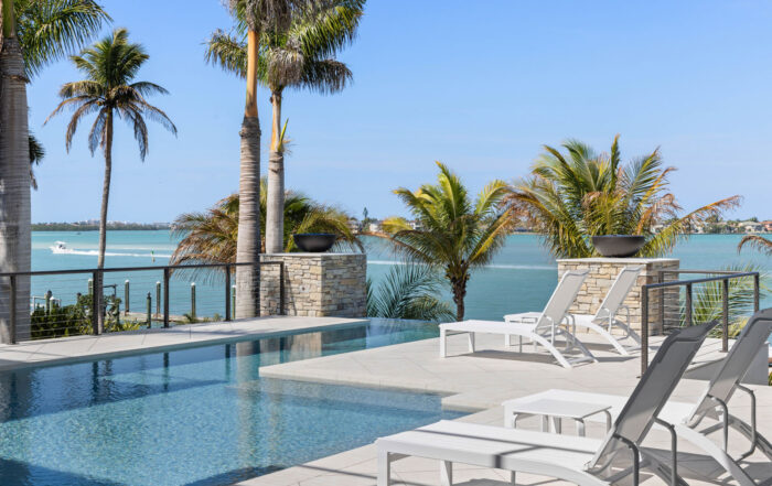 Infinity-edge pool terrace with waterfront views and outdoor living space