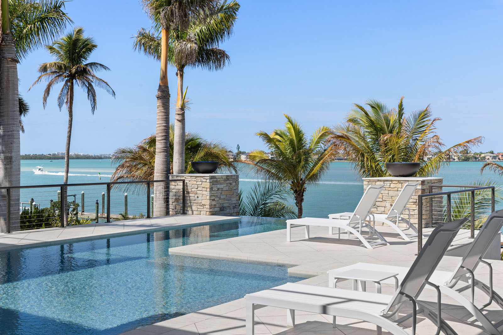 Infinity-edge pool terrace with waterfront views and outdoor living space